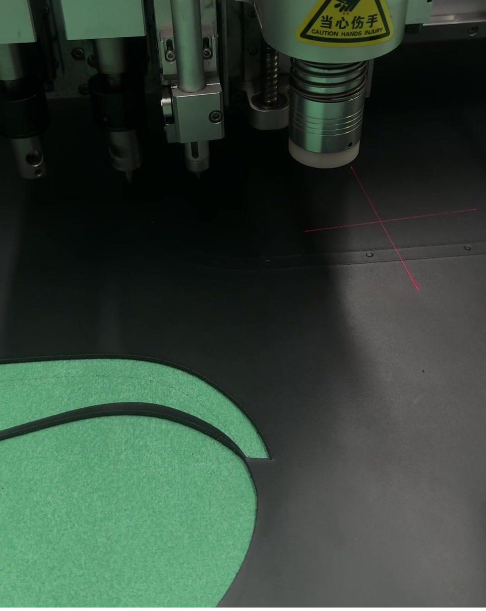 CNC cutting head following a laser guide through leather with precision